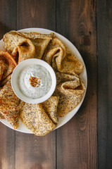 Delicious poppy seed crepes (blinis) and sour cream sauce with dill served on a white plate on a...