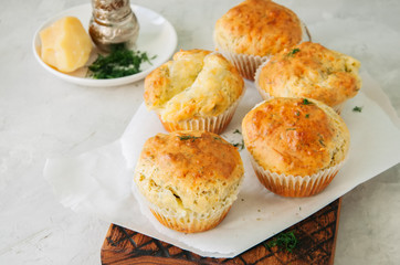 Savory double cheese muffins on a wooden board. White stone background.