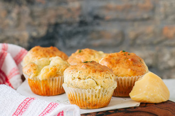 Savory double cheese muffins on a wooden board. White stone background.