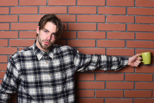 handsome guy holding cup on brick wall background