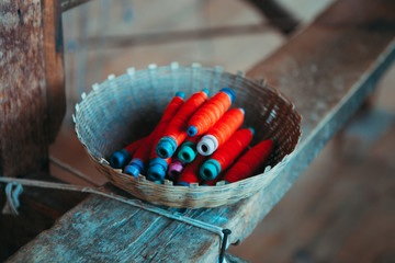 A vintage basket with a sewing kit, a red thread on the background of a tree. Factory for...