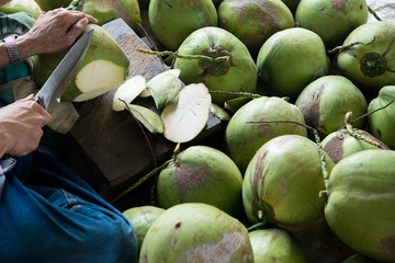 Asian man using knife peeling fresh coconut,selective focus,Fresh Coconut with Served, asian man cutting fresh coconut with knife