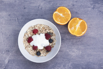 Bowl of Muesli with two orange halves on a blue stone background 