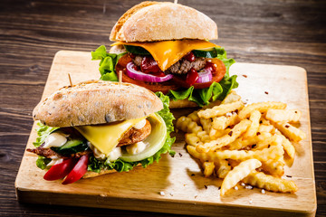 Tasty burgers with chips served on cutting board
