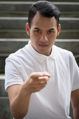 pointing man portrait; serious man pointing finger gesture; asian man points at you with serious...