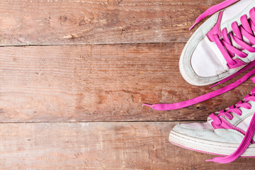 Old women's sneakers with pink laces on old boards. How to choose new sneakers? Copy space for text