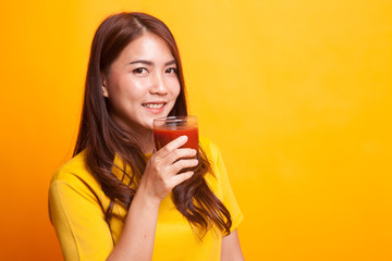 Young Asian woman drink tomato juice in yellow dress