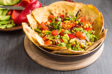 Traditional Mexican vegetarian taco salad with avocado, corn, pepper, tomatoes and beans