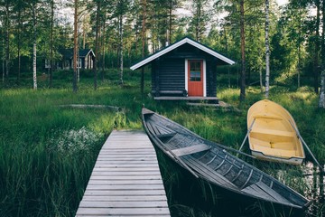 Traditional wooden hut. Finnish sauna on the lake and pier with fishing boats