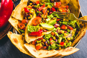 Classic Mexican taco salad with avocado, corn, pepper, tomatoes and beans with slices of tortillas