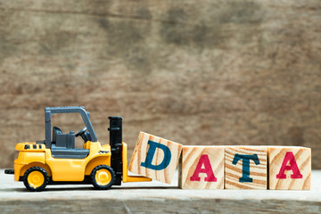Yellow toy forklift hold letter block D to complete word data on wood background