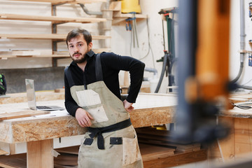 Portrait of a worker in work clothes in front of workbench tools / Portrait of man at work in...