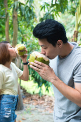 A man and woman drinking coconut water  in hands at coconut farm.