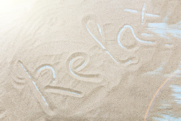 Relax handwritten in sand on a beach.