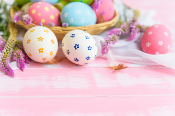 Obraz na płótnie Canvas Happy easter! Colorful of Easter eggs in nest with paper star, flower and Feather on pastel color bright pink and white wooden background.