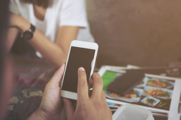 Close up of women's hands holding cell telephone with blank copy space scree for your advertising text message.He is sitting in restaurant or cafe.