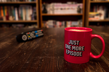 Cup of coffee with inscription Just one more episode and tv remote controller