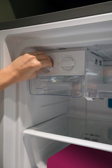 Closed up woman hand twisting for ice from the ice maker