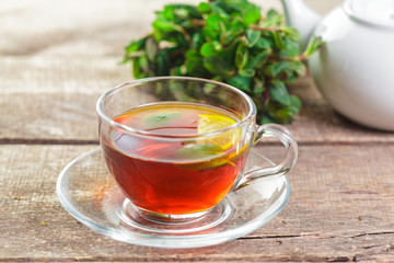 cup of black tea with mint leaves on a wooden table