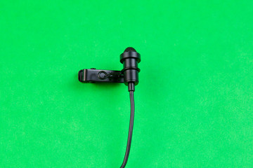 Miniature microphone of the buttonhole. A small microphone for recording quality sound on a green background.