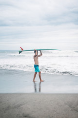 surfer carrying surfboard on head in Bali, Indonesia