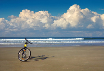 Obraz premium yellow bicycle on the beach by the sea in sunny weather