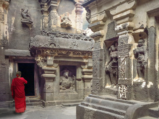 Kailas palace in Ellora caves complex carved into the rock. in India. Woman in red sari on the doorstep to the temple