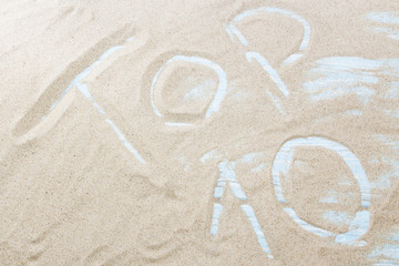 The word top 10 is written on the golden sand of the beach by the sea. Concept - the ten best beaches, tours or ways to relax in the south