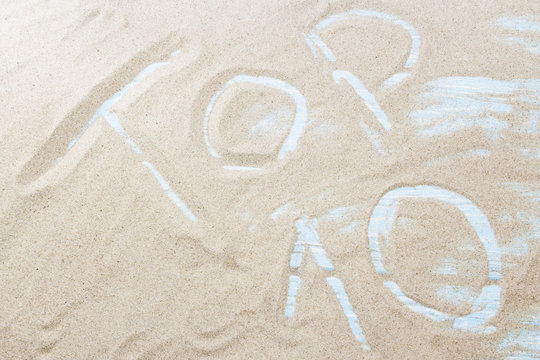 The word top 10 is written on the golden sand of the beach by the sea. Concept - the ten best beaches, tours or ways to relax in the south