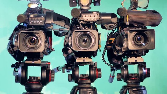 Zooming-in footage of three camcorders in a studio