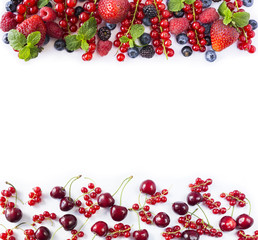 Ripe red currants, strawberries, raspberries, blackberries, blueberries, cherries and blackcurrants on white background. Berries at border of image with copy space for text. Top view.