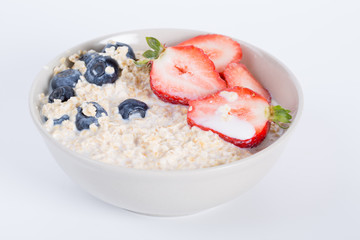 Oatmeal, Milk. A bowl of oatmeal with fresh strawberries, healthy breakfast with a cup of milk. 