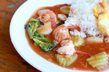 stir fried shrimp and Broccoli in thai red curry paste sauce with rice, Curry fried shrimps and cooked rice in white dish closeup on wooden table. Thai style food.