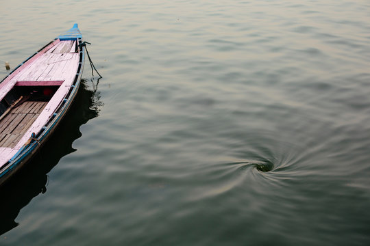 Old wooden boat and Funnel whirlpool on water surface