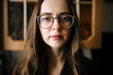 Young beautiful housewife in glasses mood portrait. Long haired classical beauty with emotional face expression looking at camera. Pretty woman standing in kitchen. Mess at home. Old fashioned style.