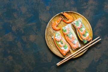 Obraz na płótnie Canvas Spring rolls with shrimps in a wooden plate. Vietnamese food. Asian food. Top view, copy space.