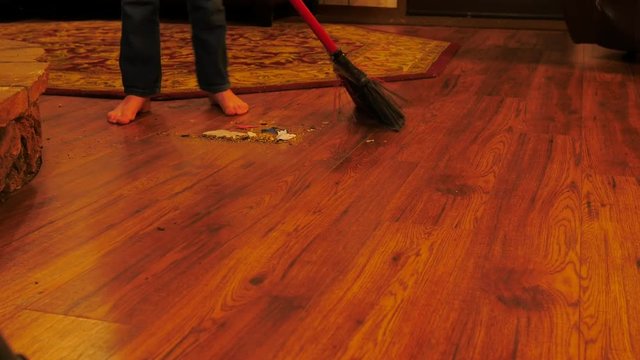 Little kid lower halk sweeping wood floor in bare feet