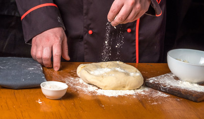 Cook with dough in a dark jacket. Cooking in the restaurant.