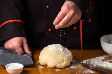 Cook with dough in a dark jacket. Cooking in the restaurant.