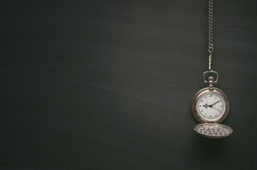 Education background with copy space. Pocket watch on blackboard surface background with copy space.