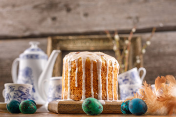Delicious home-made Easter cake in sugar-coated glaze close-up. Festive treat. Quail eggs traditionally painted for Easter. A postcard in a rustic style.
