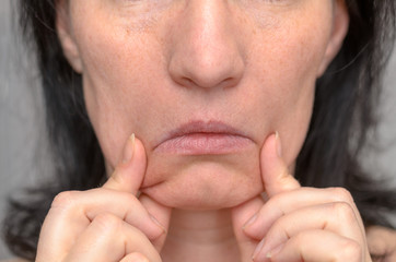 Fototapeta premium Woman pulling down the sides of her mouth