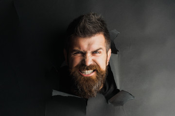 Angry male head looking through paper hole. Portrait angry man peeping through black paper hole....