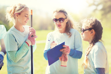 volunteering, charity, people and ecology concept - group of volunteers with clipboard in park