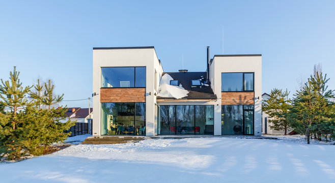 A modern house with large panoramic windows in the background of a snow-covered landscape