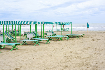 Daylight view to vibrant green sunchairs and sunshades on beach