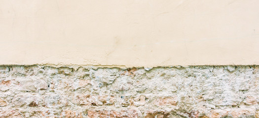 Old weathered vintage brick wall with broken plaster and pavement. Grungy urban background.