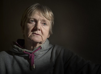 Portrait image of a depressed mature woman in a dark room, taken with copy space 