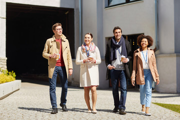 business, education and corporate people concept - happy international group of office workers with conference badges drinking coffee and talking outdoors