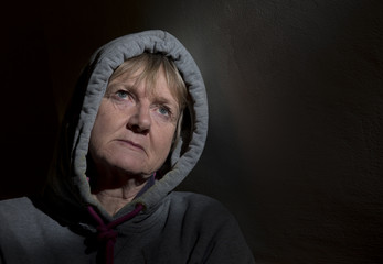 Portrait image of a depressed mature woman in a dark room, taken with copy space 